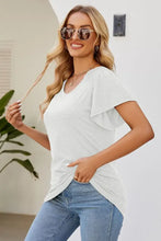 Woman in smocked round neck flutter sleeve T-shirt with blue jeans