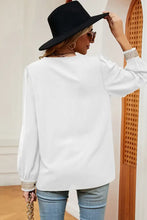 Woman in long sleeve V-neck T-shirt, blue jeans, and black hat