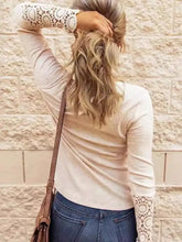 Woman in long sleeve Henley shirt with lace cuffs, button round neck, jeans, bag