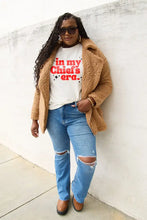 Woman in tan teddy coat, ripped jeans, brown platforms, Simply Love Chiefs era short sleeve T-shirt