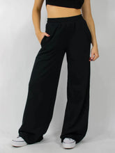 Black wide leg pants with elastic waist wide fit and side pockets featuring a relaxed flowing silhouette