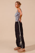 Black loose fit jogger pants with white vertical stripes and double lined decorative ties along side seams