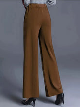 Brown high-waisted wide leg pants with smooth flowing fabric featuring care instructions for machine wash and tumble dry