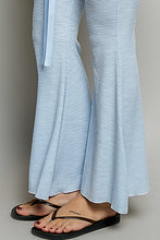 Light blue flare pants made from breathable textured ribbed knit fabric with a matching tie belt
