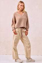 Beige ribbed knit v-neck sweater with long sleeves paired with drawstring striped twill barrel pants