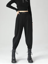 Black high-waisted tapered pants with pleats and a metallic buckle belt loop made from polyester fabric for perfect fit