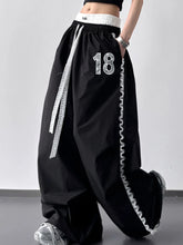 Black wide leg pants with white lace trim and 18 number detail featuring a drawstring wide leg design