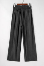 Black smocked high waist wide leg pants made of lightweight fabric with elastic waistband and side pockets
