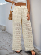 Cream-colored wide leg pants in lace fabric featuring a high waist and decorative button wide closure