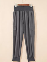 Gray cargo jogger pants with elastic high waist, side pockets, and cuffed ankles in a high waist pocketed design