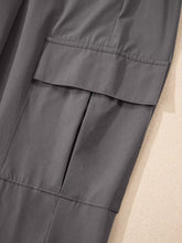 Gray elastic high waist pocketed cargo jogger pants with durable fabric and reinforced stitching on large flap pocket