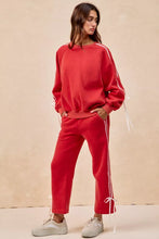 Red sweatshirt with white side stripes and drawstring cuffs featuring lined bow details fleece design