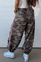 Camo print drawstring waist joggers featuring camouflage cargo pants with a red white and black striped side panel