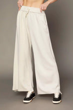 Cream-colored umgee wide leg pants with elastic drawstring waistband and side pockets for comfortable wear