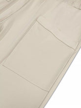 Beige utility pocket with clean stitching on plus size relaxed fit casual pants showing subtle texture detail