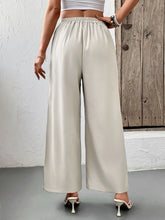 Cream-colored satin slit wide leg pleated pants with elastic waistband for a comfortable fit