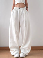 White loose-fitting wide leg pants with elastic waistband and subtle side seam detailing for comfortable wear