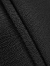 Black crinkled fabric with subtle sheen and textured weave on plus size high waist wide leg pants with smocked waist