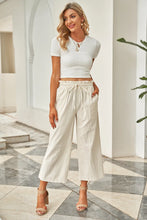 Cream-colored drawstring paperbag waist wide leg pants with high waist and subtle pleats for elegant wear