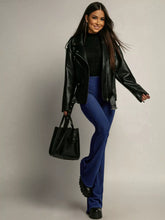 Black leather tote bag with structured handles and minimalist design complementing high-waisted flared pants