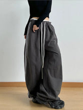 Dark gray wide leg drawstring pants with white side stripes and a loose fit ideal for casual wear