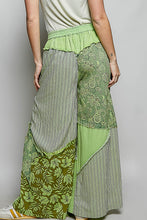 Patchwork wide-leg pants in green shades with striped lace floral patterns partial elastic waistband and big star patch