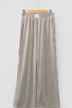 Striped wide-leg trousers with vertical black and beige stripes featuring elastic high waist and pockets on lightweight fabric