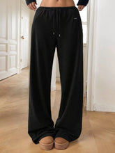 Black relaxed fit drawstring pants featuring wide-leg sweatpant design with elastic waistband for comfort