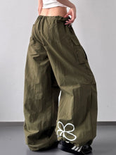 Olive green drawstring wide leg cargo pants with white floral design on lower leg in cotton fabric