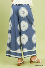 Denim blue umgee wide-leg pants with bold white abstract border print and contrasting white trim along the hem