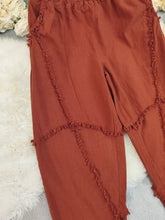 Rust-colored frayed edge harem pants featuring textured trim along the seams for a stylish boho look