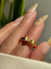 Woman’s hand with gold bow knot ring and pointed nails