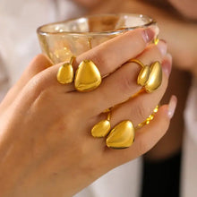 Womans hand with 18k gold-plated stainless steel irregular bypass ring holding glass