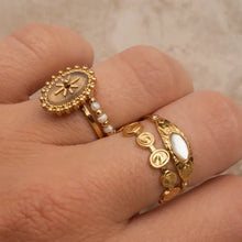 Three 18k gold-plated rings on fingers with white accents and sunburst design