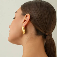 Woman’s ear with 18k gold-plated stainless steel stud earring and low ponytail