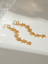 Two 18k gold-plated steel cutout star drop earrings in golden hue