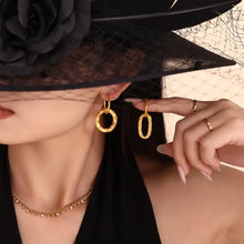 Woman in black veiled hat wearing 18K gold-plated titanium steel annulus earrings