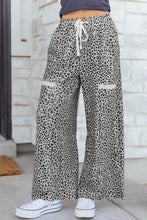 Animal print wide leg terry knit pants with leopard print, white drawstring waistband, and cream pocket flaps