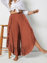 Plus size rust-colored ruffled wide leg pants with side slits and ruffled hem in flowy fabric