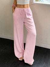 Soft pink tied wide leg pants with drawstring waist and subtle vertical pleats offer comfortable stylish wear