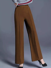Brown high-waisted wide leg pants with subtle vertical pleats featuring care instructions for machine wash and tumble dry