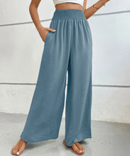 Light blue high-waisted wide leg pants with smocked waistband and subtle textured fabric for a comfortable fit
