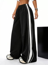 Wide leg striped black track pants with bold white vertical stripes down the sides for casual wear