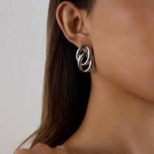 Silver stainless steel twisted oval stud earring on woman’s ear