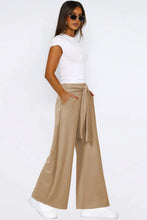 Beige tied pocketed wide leg pants with a tied waistband and side pockets in a relaxed fit design