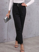 Black high-waisted belted paperbag waist pants with ruffled waistband and silver-toned circular belt buckle