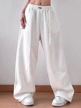 White loose-fitting wide leg pants with elastic waistband and side drawstrings for comfortable everyday wear