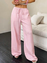 Soft pink tied wide leg pants with drawstring waist and subtle vertical pleats in wide leg style