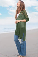 Olive green long sleeve cardigan with slit open sides, wide-leg jeans, white top