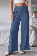 Blue pleated wide-leg trousers with a crossed waist in solid color textured soft flowing fabric